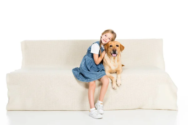 白で隔離の子とソファーに座っていた犬の笑みを浮かべて — ストック写真