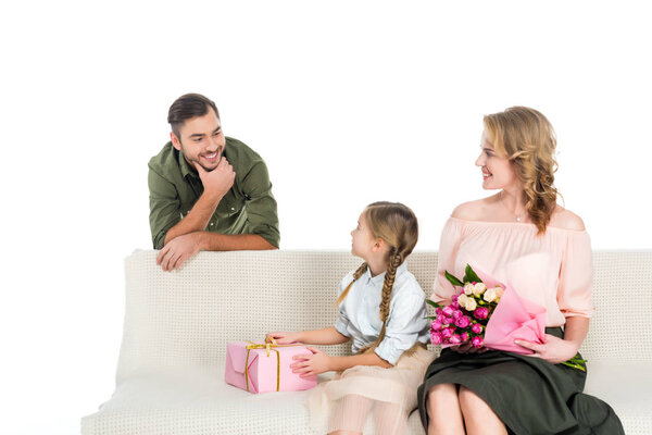 man looking at happy family with gifts on sofa isolated on white
