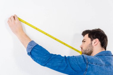 man measuring wall with tape measure on white clipart