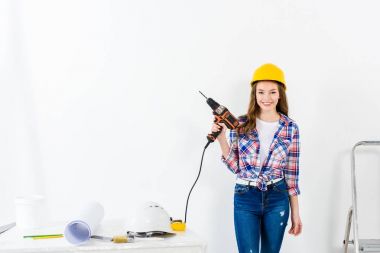 young woman holding drill and looking at camera clipart