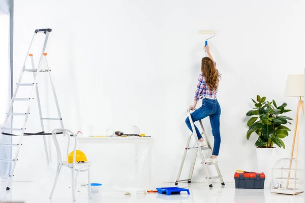 はしごと絵画の壁に立っている女の子の背面図 — ストック写真