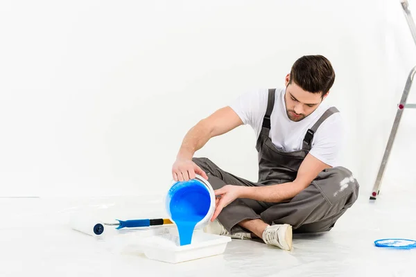 handsome man pouring paint into tray