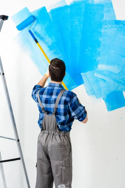 Rückansicht Eines Mannes Der Wand Mit Blauer Farbe Bemalt — Stockfoto