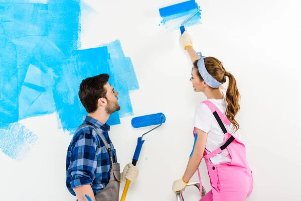男朋友和女朋友画墙壁与蓝色油漆 — 图库照片