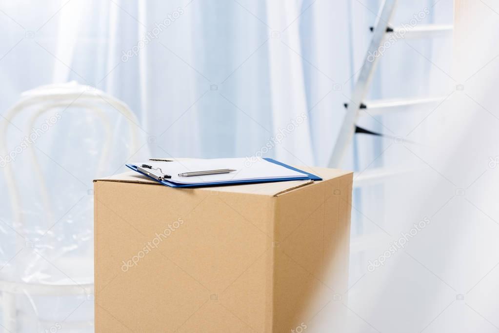 clipboard with pen on box in empty room