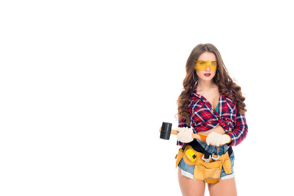 beautiful sexy girl in goggles and gloves with tool belt holding hammer, isolated on white