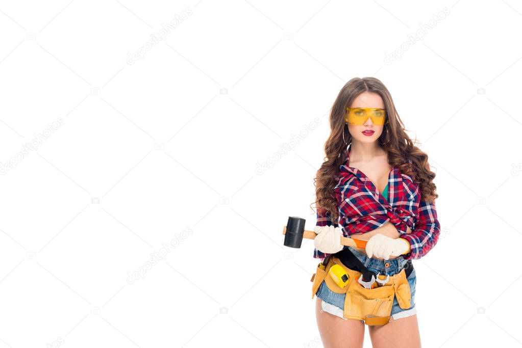 beautiful sexy girl in goggles and gloves with tool belt holding hammer, isolated on white