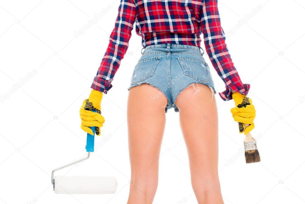 back view of sexy girl in gloves holding painting roller and brash, isolated on white