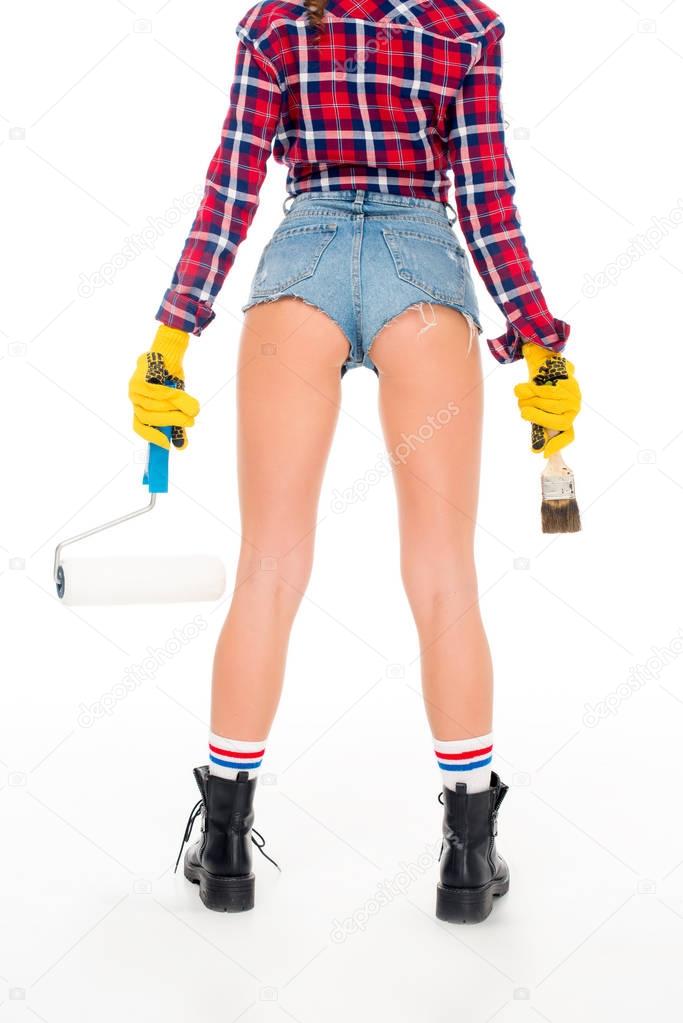 rear view of sexy girl in gloves holding painting roller and brash, isolated on white