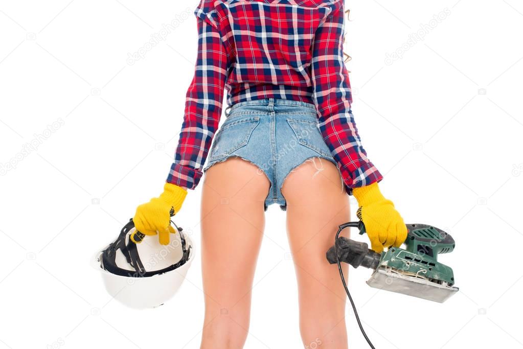cropped view of sexy girl in gloves holding safety helmet and grind tool, isolated on white