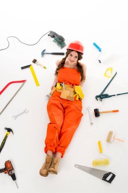 overhead view of girl in overalls and hardhat lying on floor with different equipment and tools, isolated on white clipart