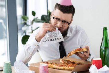 İşyerinde pizza yemek başında parti koni ile işadamı portresi