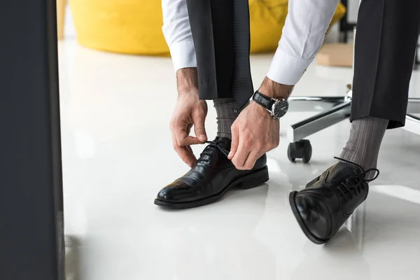 オフィスで靴ひもを結ぶ実業家の部分的なビュー — ストック写真