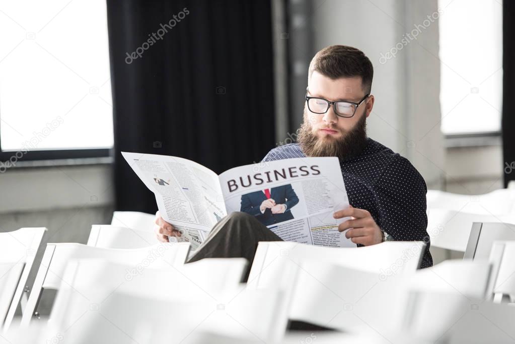 focused businessman reading newspaper in meeting room