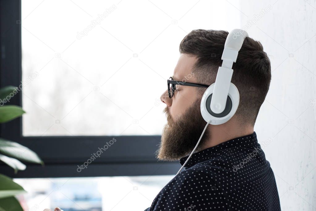 side view of man with eyes closed listening music in headphones