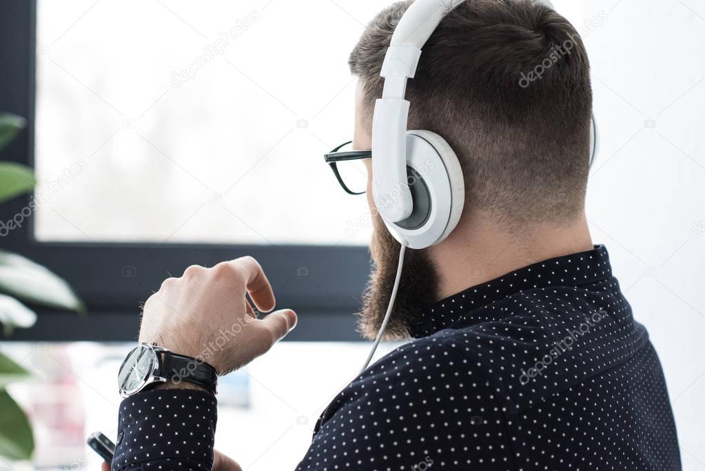 partial view of man with smartphone listening music in headphones