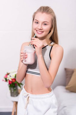 Kameraya bakarak saman ile gülümseyen milkshake mason kavanoza ile genç kadın