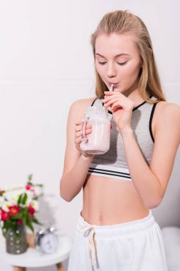 mutlu genç kadın mason kavanoza saman ile milkshake içme