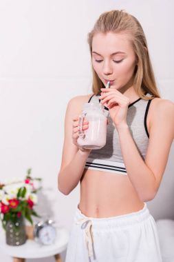 happy young woman drinking milkshake from mason jar with straw clipart