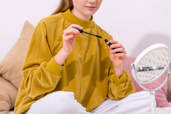 cropped shot of young woman applying mascara