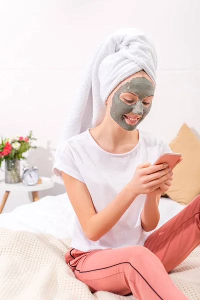 Młoda Kobieta Glinki Kosmetyczne Maski Przy Użyciu Smartfona Domu — Zdjęcie stockowe