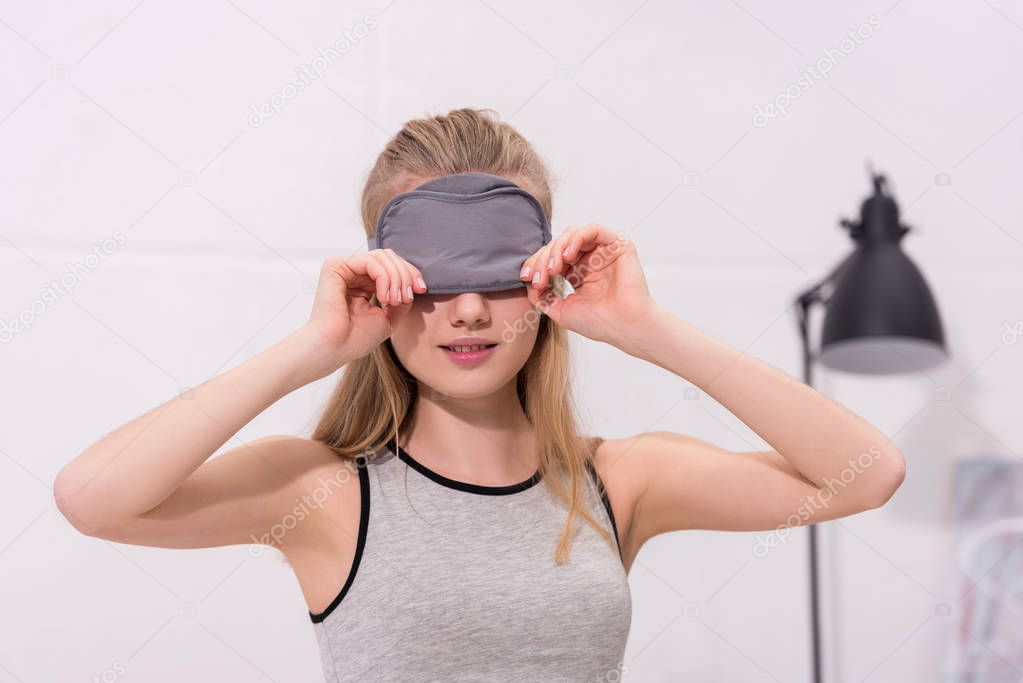 beautiful young woman putting on sleep mask