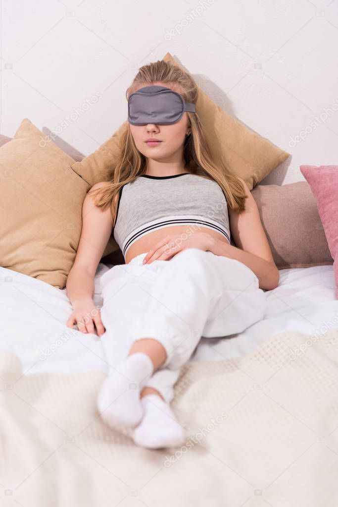 attractive young woman sleeping in eye mask in bed