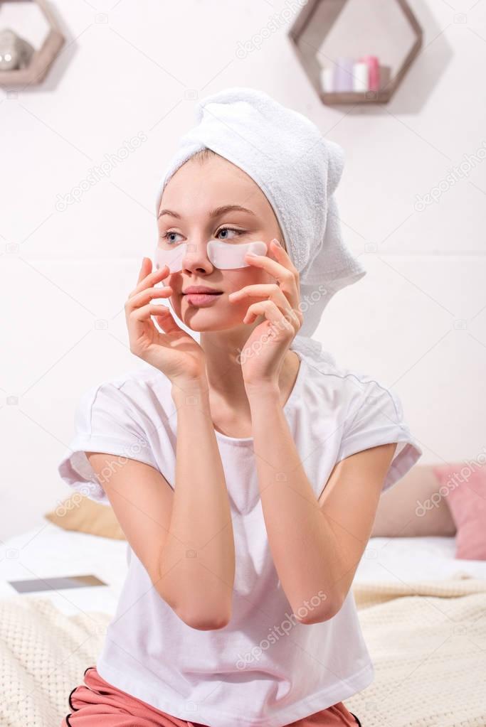 attractive woman spplying cosmetic facial patches at home