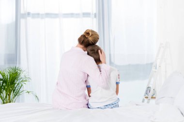 Anne ve oğlu yatağın üstüne otururken kucaklayan dikiz