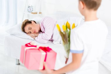 o yatakta uyurken hediye ve çiçek anne üzerinde anneler günü sabah holding oğlu
