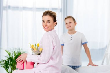 mother with gift and flower bouquet presented by son on mothers day morning clipart