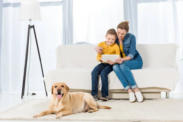 母亲和儿子使用平板电脑和可爱的狗躺在地板上的前景 — 图库照片