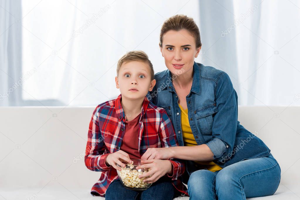 interested mother and son watching movie together with popcorn