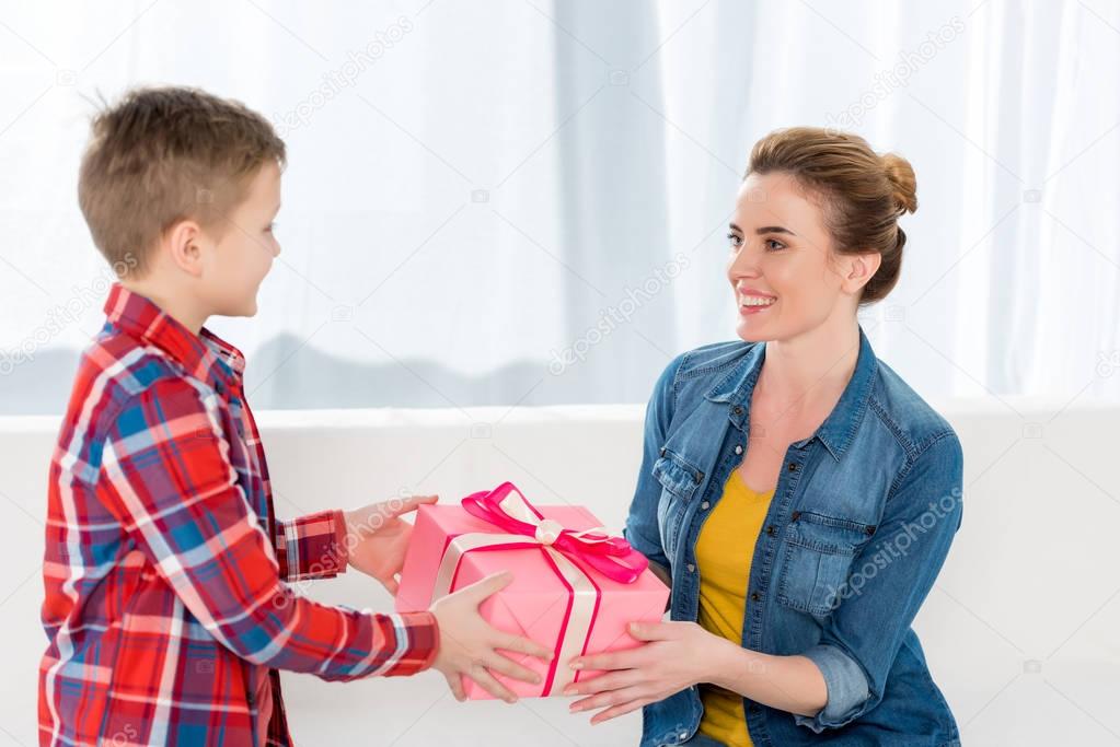 little son presenting mothers day gift to his mother