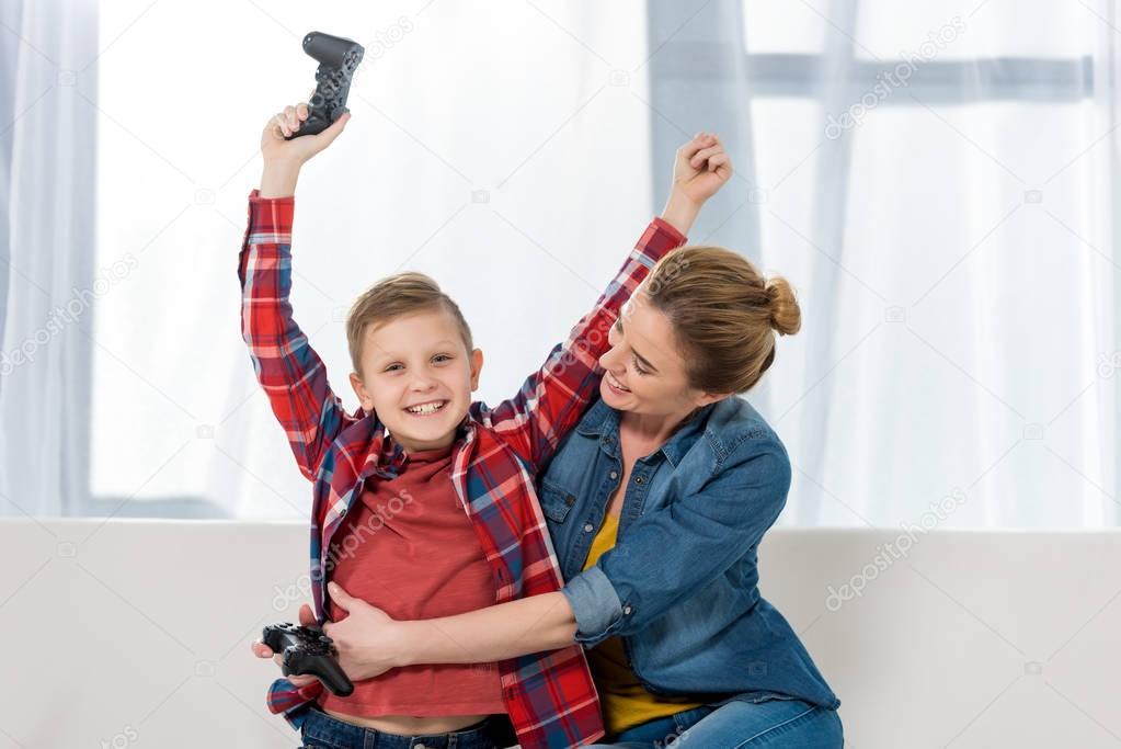 mother embracing her celebrating son while playing video games together