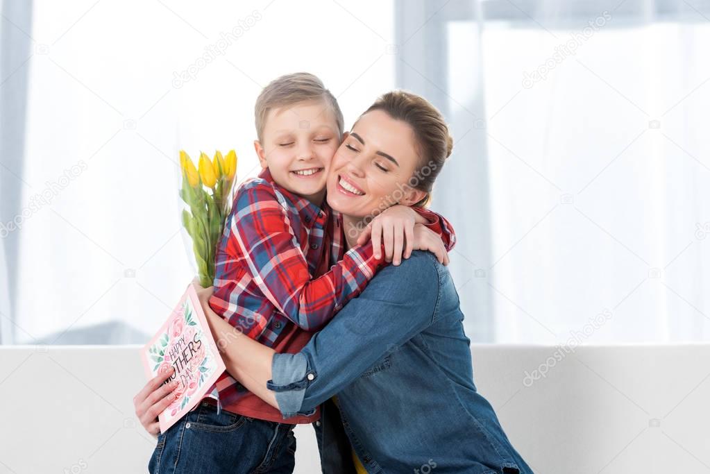 smiling mother and son embracing on mothers day after he gave her flowers