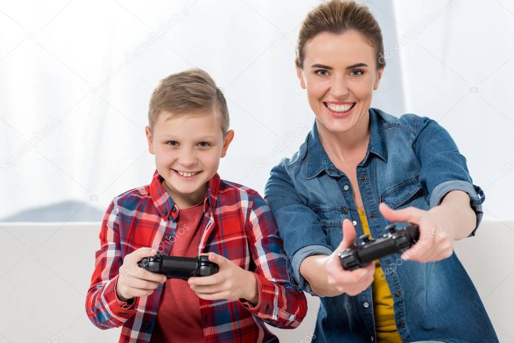 excited mother and son playing video games with gamepads together