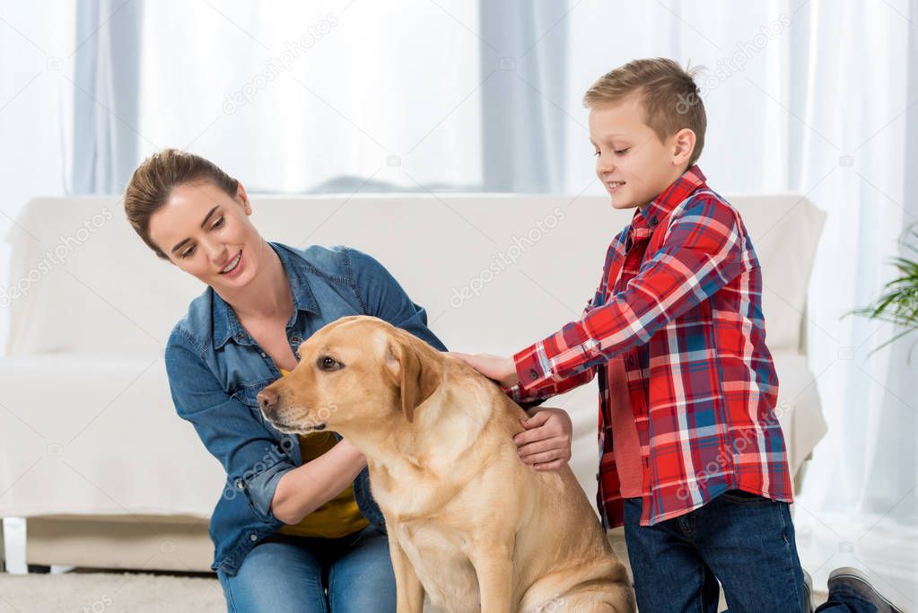 mother and son petting their yellow labrador dog