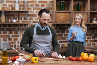 Koca kesme sebze ve kadeh şarap ile ayakta karısı