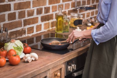 cropped image of woman stirring vegetables on frying pan clipart