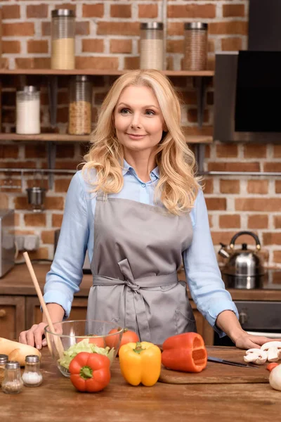 Mujer Sonriente Pie Cerca Mesa Cocina Mirando Hacia Otro Lado — Foto de stock gratis