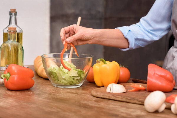 cropped image of woman mixing salad in glass bowl