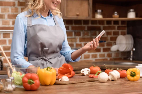 Περικομμένη Εικόνα Της Γυναίκας Που Βλέπουν Smartphone Στην Κουζίνα — Φωτογραφία Αρχείου