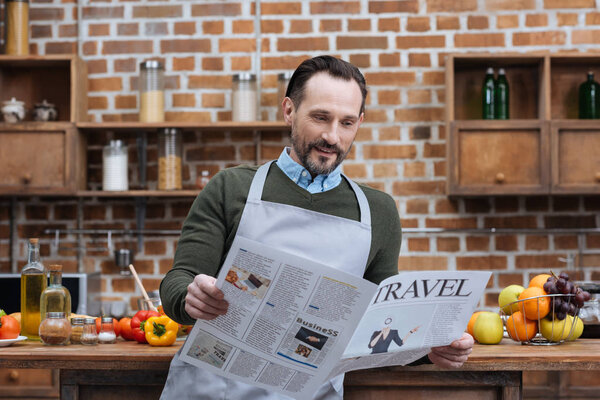 man reading travel newspaper in kitchen