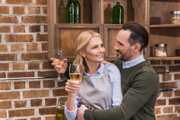 husband and wife with glasses of wine in kitchen
