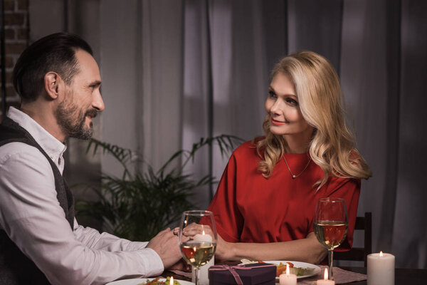 side view of couple holding hands and looking at each other during dinner