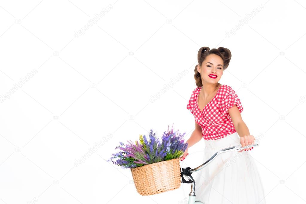 attractive pin up woman on bicycle with basket of flowers isolated on white