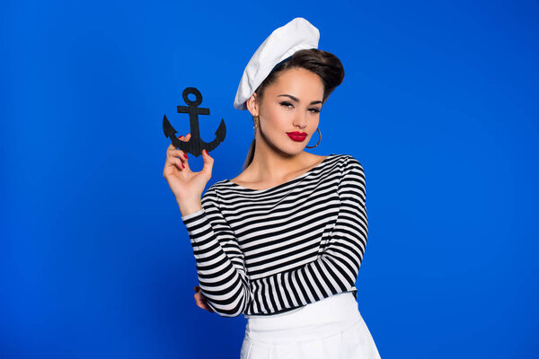 portrait of fashionable young woman in retro clothing with anchor in hand isolated on blue