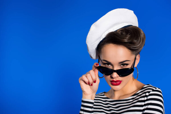 portrait of stylish woman in retro clothing and sunglasses isolated on blue