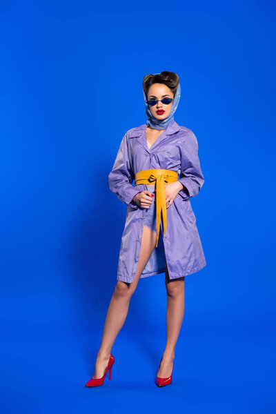 stylish woman in retro clothing and sunglasses isolated on blue